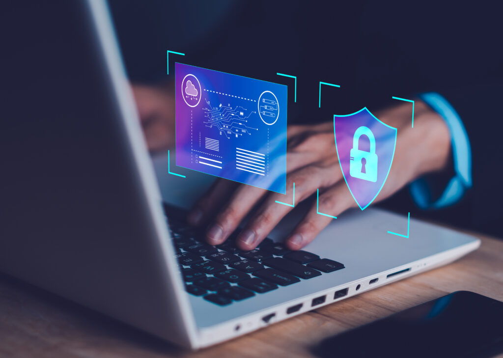 A person typing on a laptop with digital security icons, including a lock and data symbols, overlaying the image. This visual represents the importance of cybersecurity in protecting sensitive information and data in a digital environment.