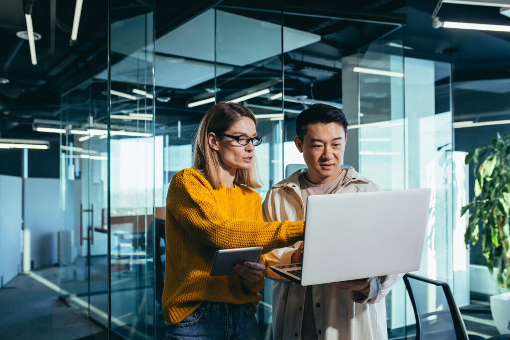 Two professionals collaborating on a laptop in a modern office, discussing Managed IT solutions. Managed IT services enhance business efficiency through proactive technology support and maintenance.